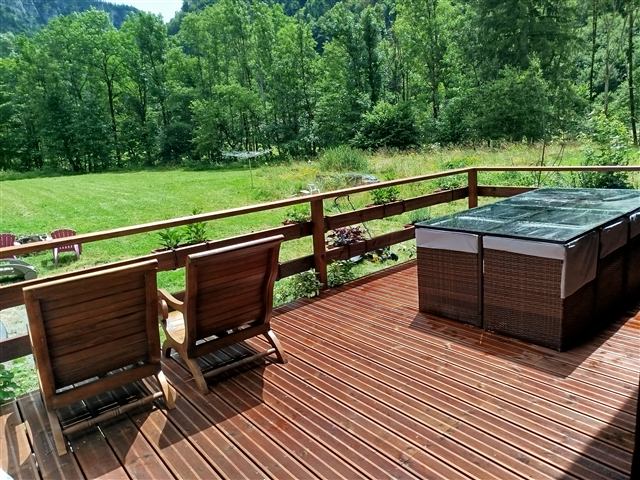Terrasse en bois du chalet Tyson City avec salon de jardin face à la montagne